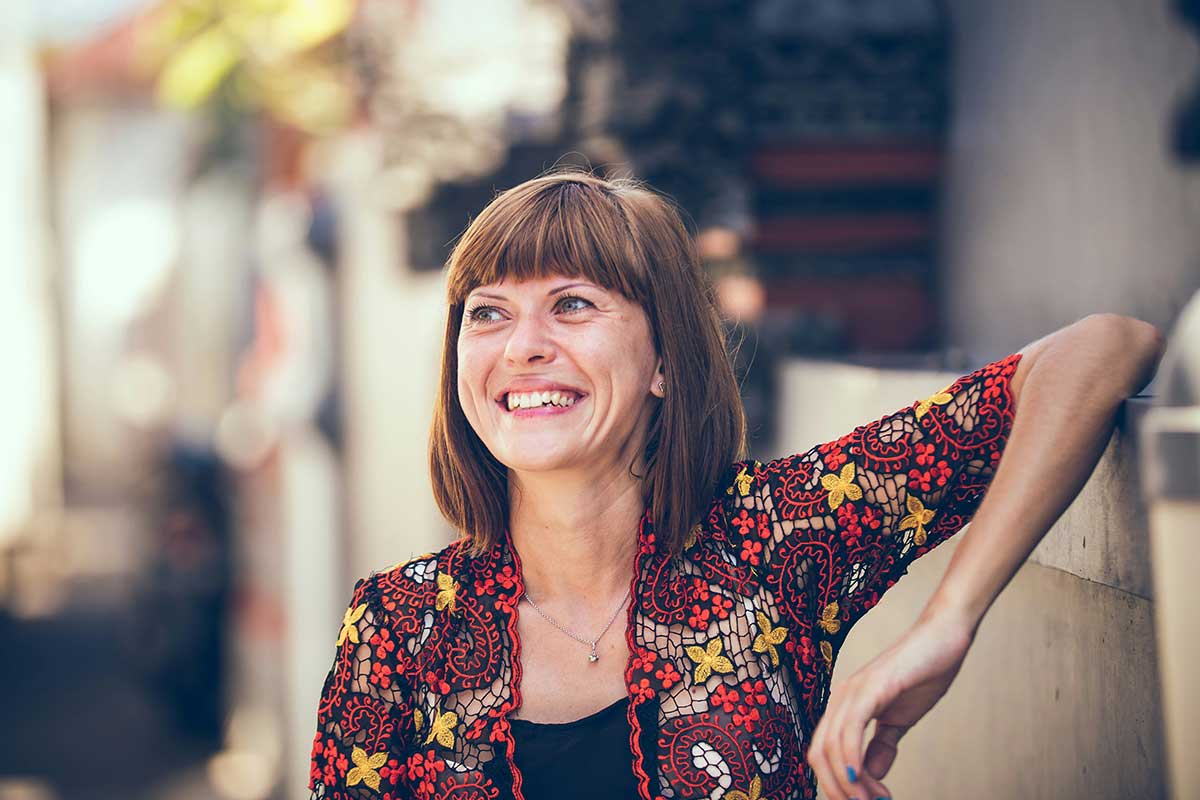 Woman In Floral Themed Cardigan Leaning On Fence In Bokeh Photography