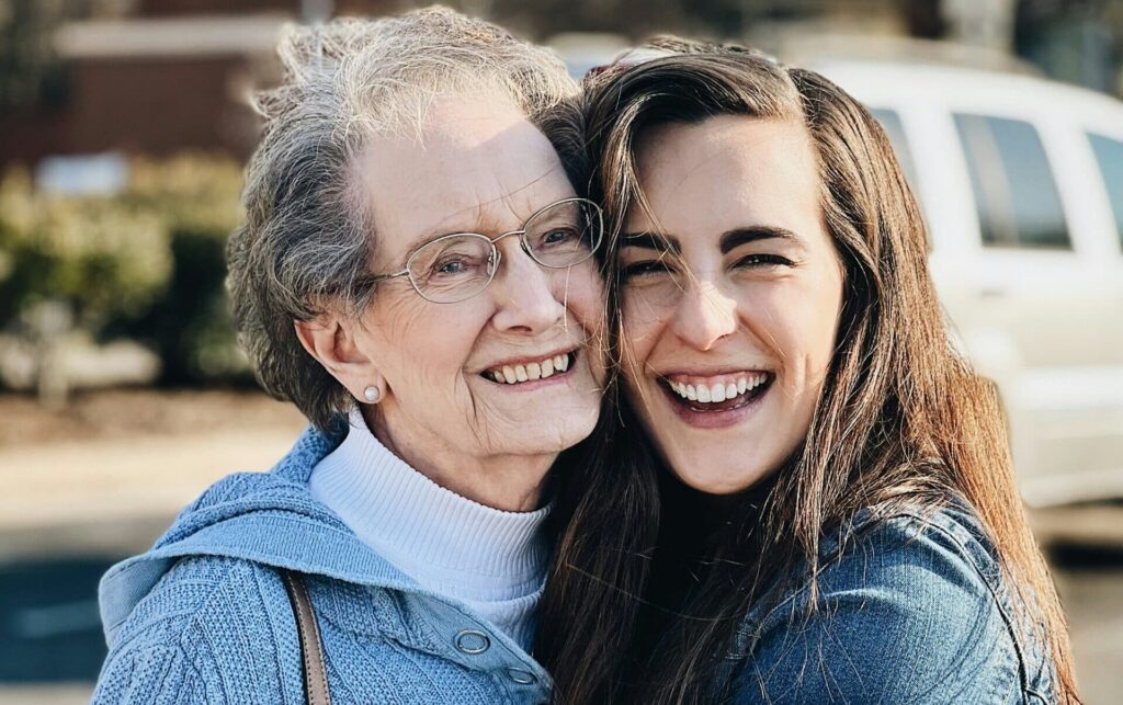 A mother and daughter hugging warmly outside, capturing the supportive relationships often navigated by the sandwich generation
